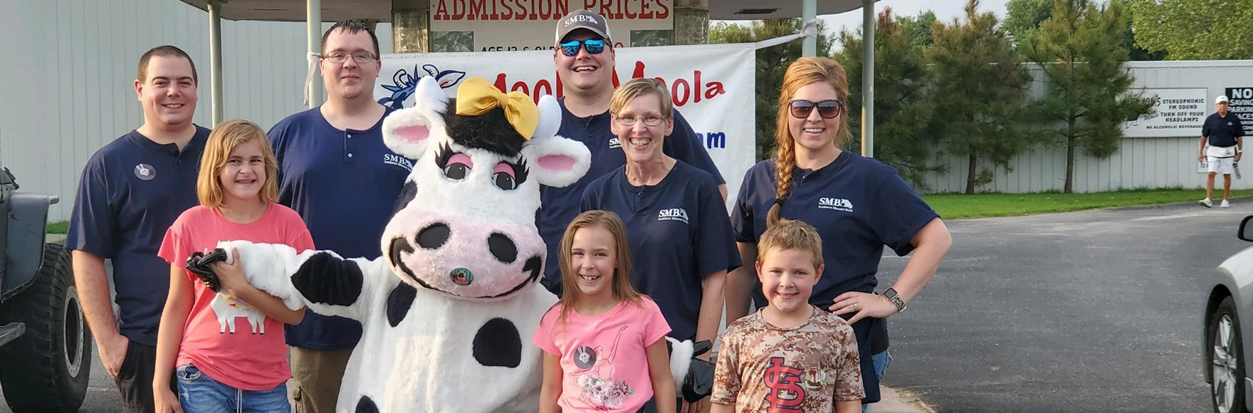 a group of people taking a picture with a cow mascot